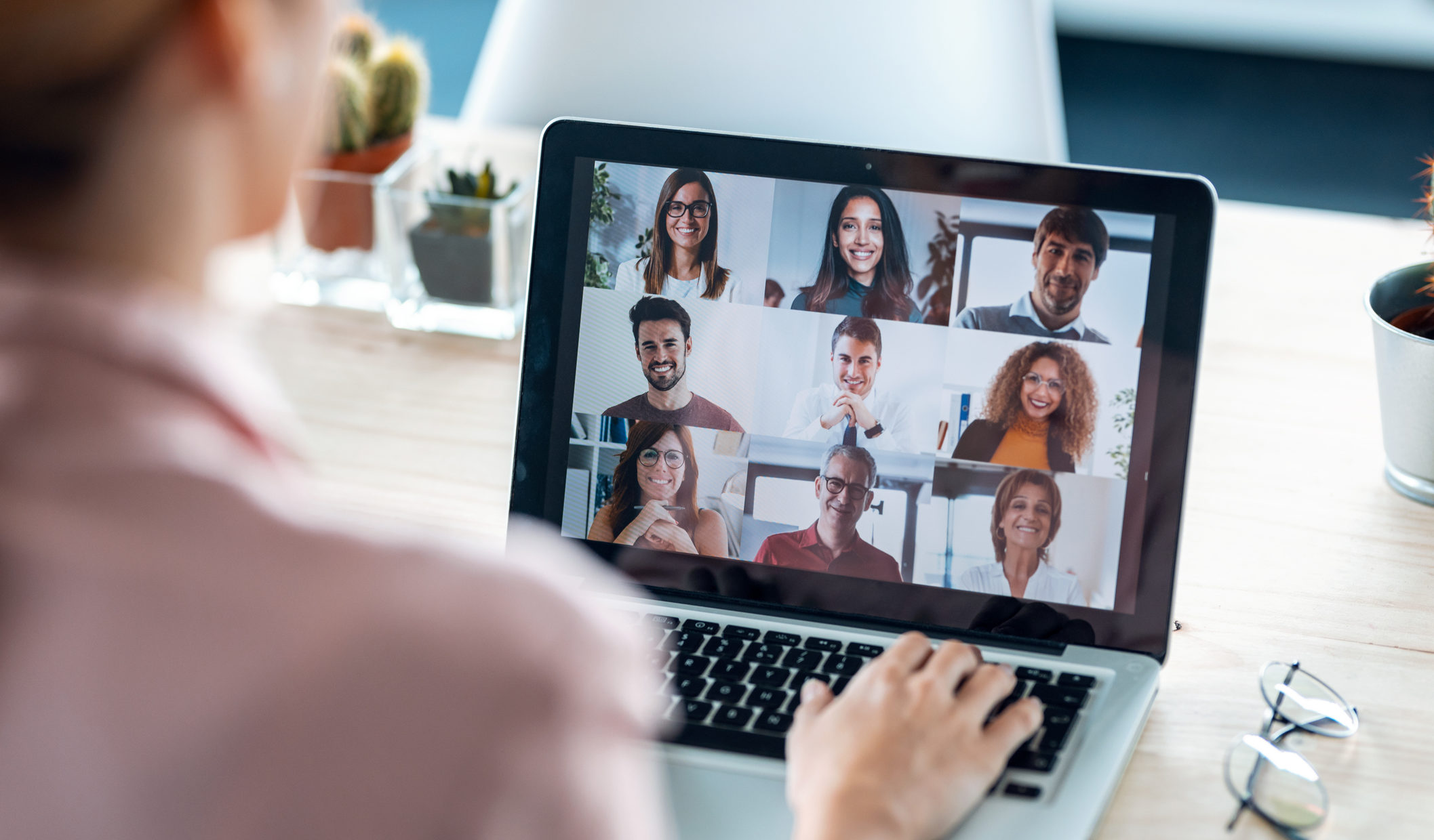 Female employee speaking on video call with diverse colleagues on online briefing with laptop at home.
