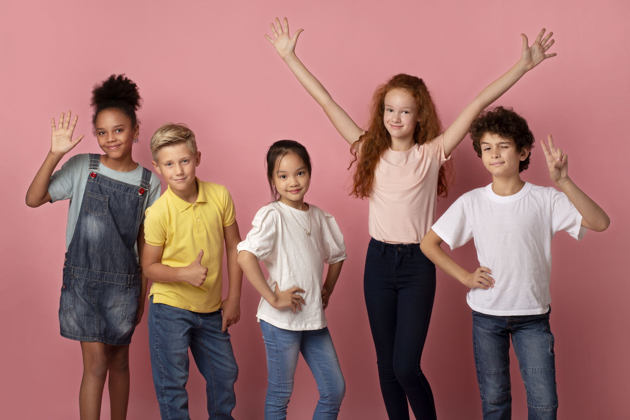 Cool multiethnic schoolchildren showing various gestures over pink background