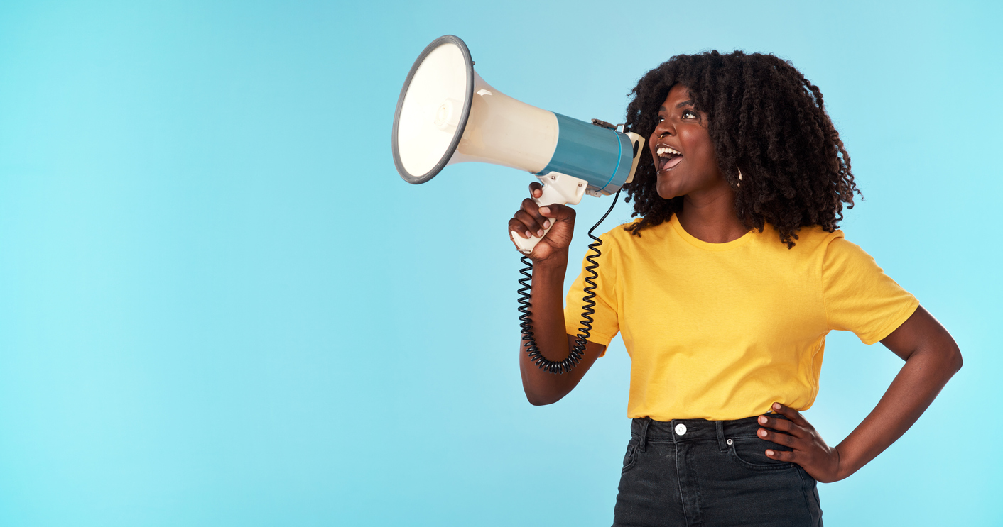 Studio shot of an attractive young woman using a megaphone against a blue background