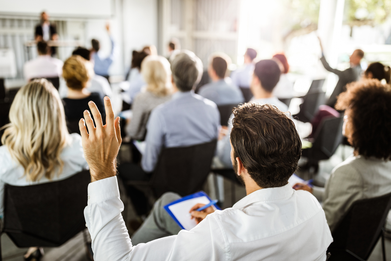Back view of a businessman raising his hand on a seminar.
